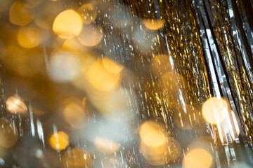 Holographic festive background with shiny tinsel and glitter. Gold and silver bokeh create a New...