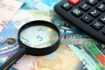 Kuwaiti dinar currency money bills and calculator with magnifying glass close up. The concept of taxation and money count