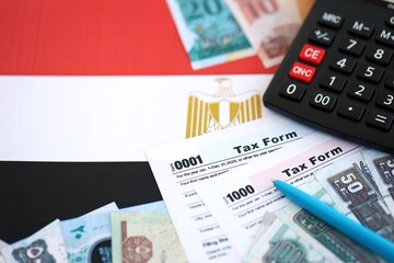 Egyptian pound money bills and calculator with tax form on flag close up. Taxation and accounting concept
