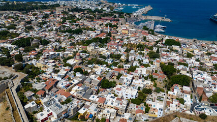 Aerial view of terracotta rooftops nestled against the azure sea and harbor dotted with yachts, ancient walls, Rhodes, Greece.