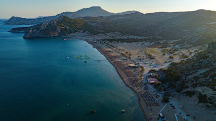 Aerial view of the beach where the sapphire sea kisses the golden sand under the gaze of mountainous silhouettes, Kolympia, Rodos, Greece.