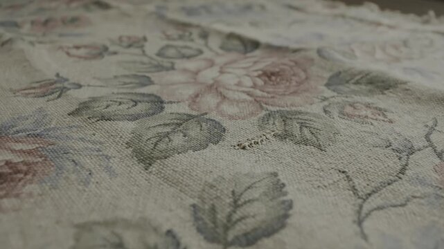 Close-up of a rustic vintage fabric with a beautiful faded rose floral pattern, showcasing intricate texture and classic...