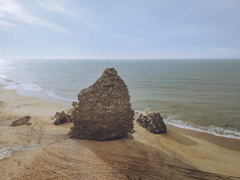 Aerial view of the Torre del Loro, a stone structure on the sandy beach where the golden sand meets the turquoise waters, Mazagon, Andalusia, Spain.
