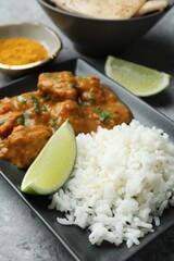 Chicken tikka masala with rice served on grey textured table, closeup