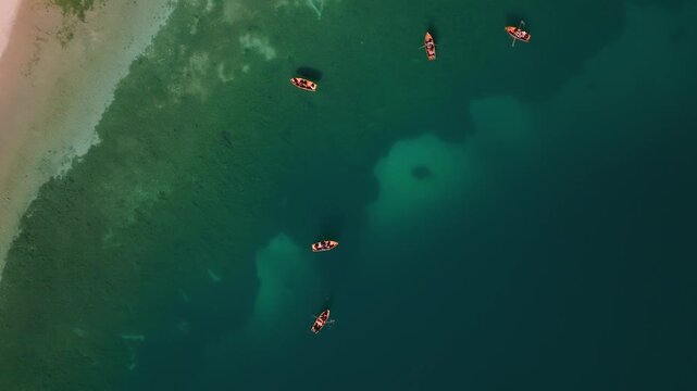 Aerial view of boats dotting the expansive, emerald waters of Lake Misurina, contrasting with the sandy shorelines, Misurina, Veneto, italy.