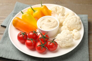 Different fresh vegetables and sauce on wooden table, closeup