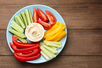 Different fresh vegetables and sauce on wooden table, top view. Space for text