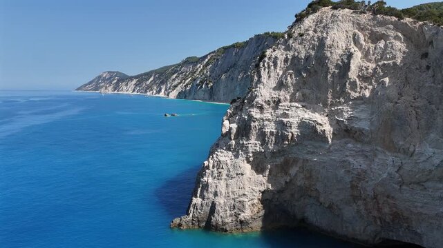 Lefkada,Aerial view pan right,panoramic view of the white steep cliffs meeting the mesmerizing turquoise calm seas.Beautiful tranquil nature and scenery,