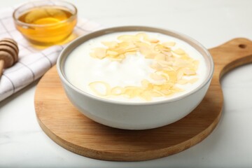 Delicious Greek yogurt with honey and nut flakes served on white table, closeup