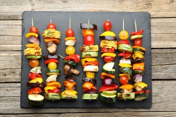 Skewers with tasty grilled vegetables on wooden table, top view