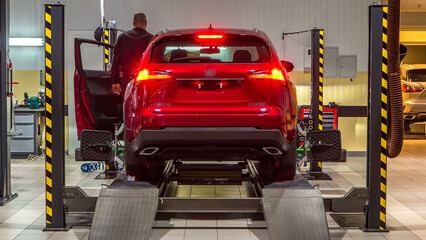 Fototapeta premium Car on stand with sensors on wheels for wheels alignment camber check in workshop of Service station timelapse.
