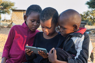 Village African Children Learning Together From Smartphone, Digital Access Kids Sharing a Mobile Phone for Education, lesson engagement © poco_bw