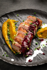 Tender seared duck fillet served with smooth pumpkin puree rich berry sauce and fresh herbs