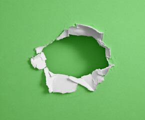 Hole In Green Wall With Torn White Paper Edges Revealing Lighter Green Center