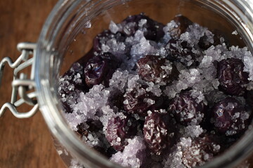 Salted black olives in a glass jar on a wooden table