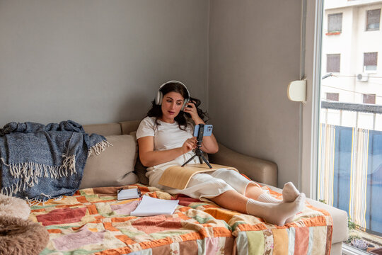 Woman streaming from home using smartphone and headphones