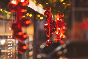 Festive red ornaments hanging in a cozy street decorated for the holiday season with warm lights...