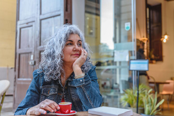 Thoughtful senior woman relaxing with coffee outside a cafe