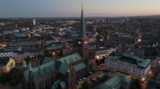 Aerial orbiting shot of the historic Aarhus Cathedral at dusk in central Aarhus, Denmark.