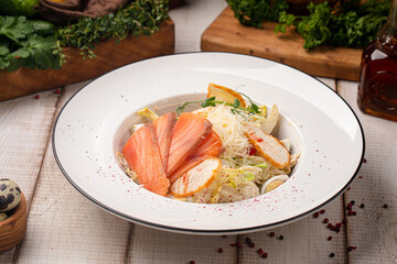 Classic Caesar salad with fresh salmon, crispy croutons and shredded cheese served on a white plate