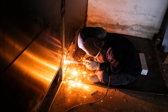 Anonymous welder with shield working on metal project