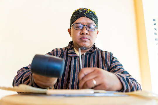 Javanese artisan working on handmade shadow puppets