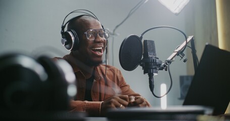 Voice Actor Records Professional Dubbing For Film or Media Project. Man at Laptop Recording Audio With Professional Studio Microphone. Technical Process Voiceover For Films, Commercials, Multimedia.