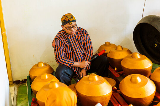Traditional Javanese musician plays gamelan instruments