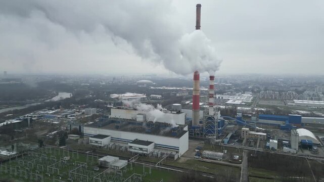 Aerial view of thermal power plant generating heat and electricity for town. Smoke emissions and industrial structures. Process of heating city homes in winter season. Emission reduction and ecology