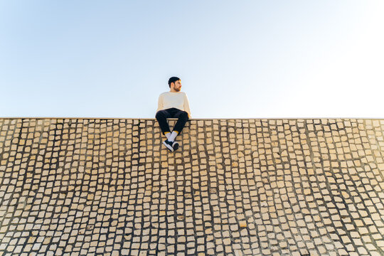 Man sitting on a wall with a mosaic design in Biarritz