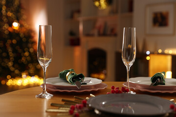 Christmas table setting with plates and glasses in festive decorated room, closeup