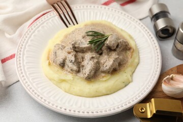 Delicious beef stroganoff with mashed potatoes and rosemary served on light table, closeup