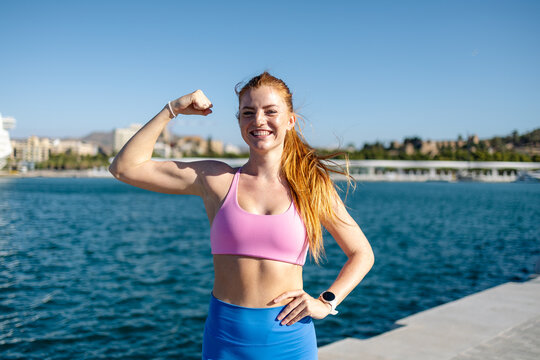 Woman in sportswear flexing by the water in Malaga