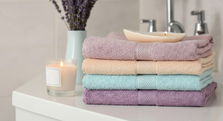 Colorful towels stacked on a bathroom counter in a calm spa scene with candlelight
