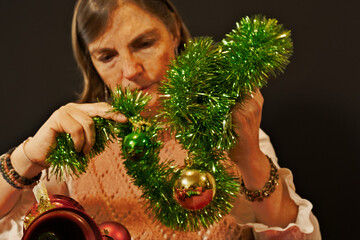 Mature woman decorating green tinsel garland for Christmas