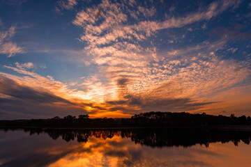 Obraz premium Mackerel Sky, clouding sunset reflected in the still water of a lake. Swithland Reservoir, Swithland, Leicestershire.