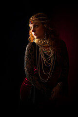A beautiful pensive bohemian woman with long red hair, dressed in a red velvet dress with black lace, wearing pearl necklaces and an amber jewel headdress