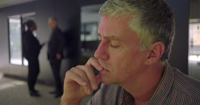 Close up of middle aged man resting face on hand with eyes slightly closed, pensive and contemplative expression in modern office setting, thoughtful moment during workday