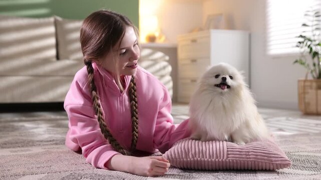 Teenage girl with Pomeranian dog on floor at home