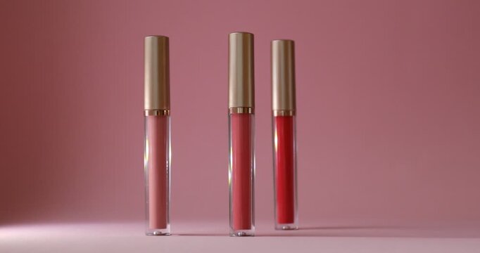 Woman putting lip gloss against color background, closeup