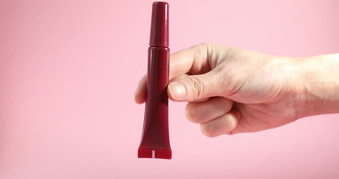 Woman with red lip gloss on pink background, closeup