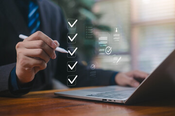 Businessman marking digital checkboxes on a laptop, showing task management, checklist review,...