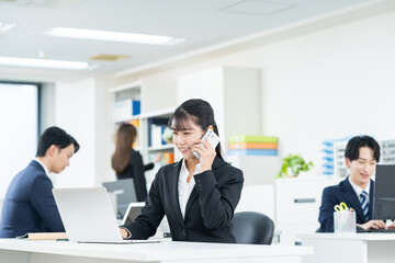 オフィスで電話する若いビジネスウーマン