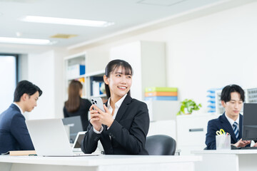 オフィスでスマホを使う若いビジネスウーマン
