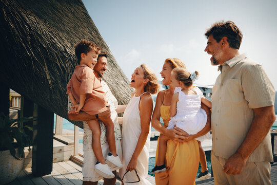 Happy family of tourists talking and laughing at a tropical resort during their summer holiday - Powered by Adobe