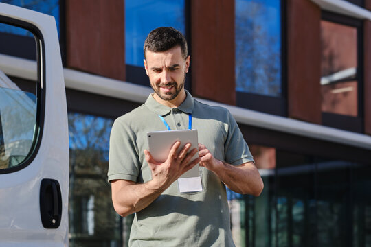 Delivery man using tablet checking order next to van