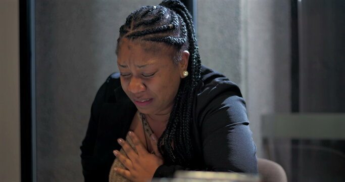Close-up of African American businesswoman crying at office table, expressing emotional pain, burnout, and vulnerability after overwhelming workplace stress