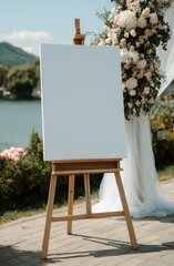 Blank canvas on easel at outdoor event; floral arrangement backdrop