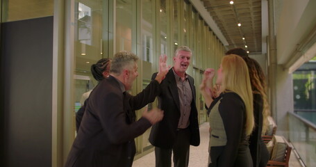 Cheerful business group giving high five indoors, coworkers acknowledging team success and unity in collaborative professional atmosphere