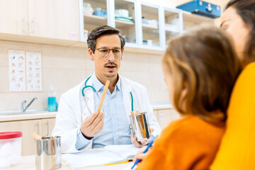 Obraz premium Male pediatrician consulting with a woman and her young child during a medical checkup in clinic.